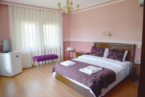 a bedroom with a large bed with purple sheets and a tv at Sarikonaklar Garden Village in Sile
