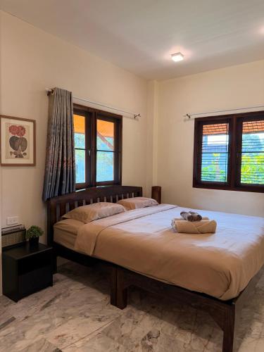 a bedroom with a large bed and two windows at Baan Yanikar in Lampang