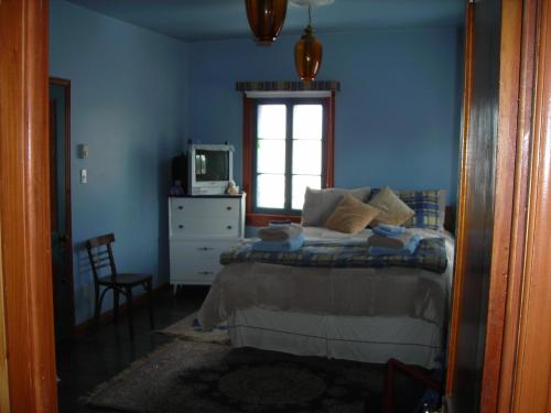 Dormitorio azul con cama y ventana en Gîte des Hauteurs et Café de la place en Saint Zenon