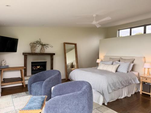 a bedroom with a bed and two blue chairs at Waiheke Luxury Blue and Green Rooms in Ostend