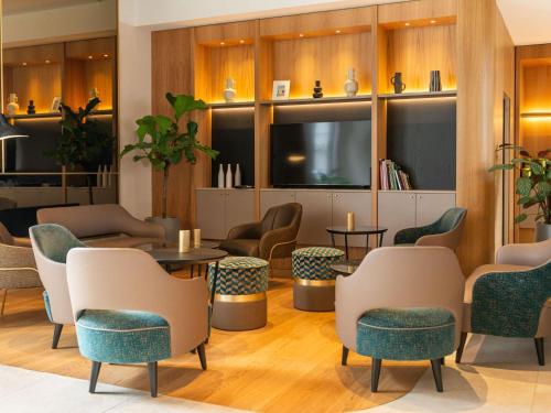 a waiting room with tables and chairs and a flat screen tv at Mercure Colmar Centre Unterlinden in Colmar