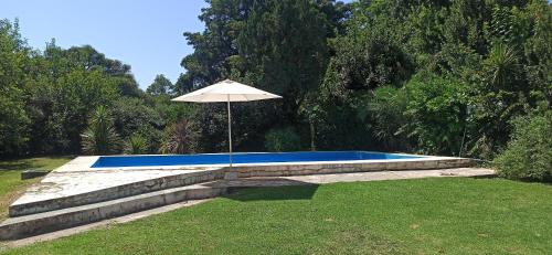 a pool with an umbrella in a yard at El buho in Roldán