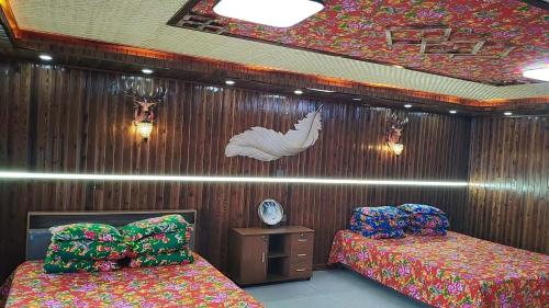 a bedroom with two beds and a wall with a bird on it at Snow Valley Xishui Dragon Soaring Inn in Wuchang