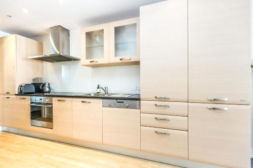 a kitchen with wooden cabinets and stainless steel appliances at Ocean Eleven 3 in Mount Maunganui