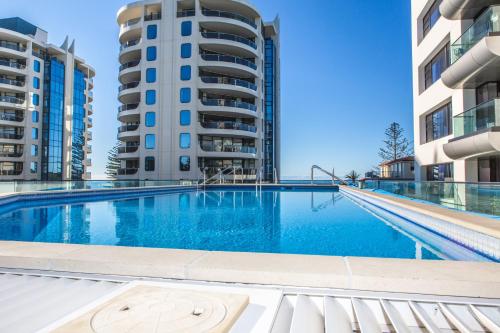 a swimming pool in the middle of two tall buildings at Ocean Eleven 3 in Mount Maunganui