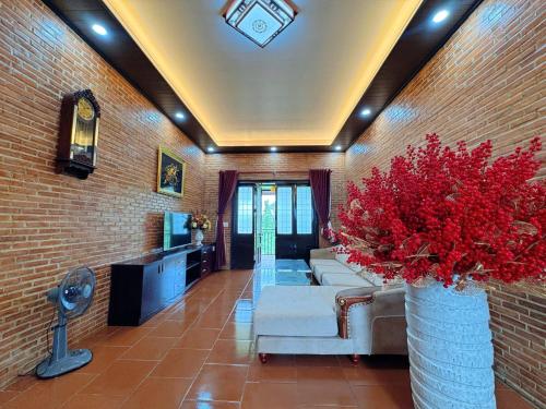 a living room with couches and a vase with red flowers at Bối Villa Bảo Lộc in Minrong Sekang