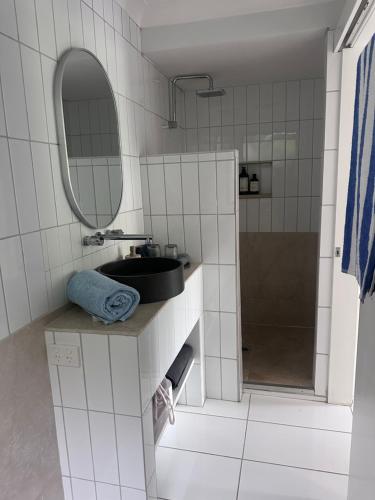 a white tiled bathroom with a sink and a mirror at Mediterranean Studio & Garden View Private Pet Friendly in Brisbane
