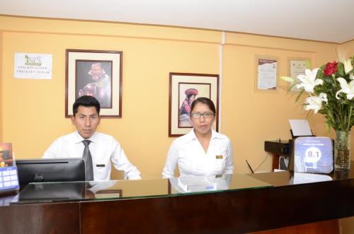 Dos personas sentadas en un escritorio con un ordenador portátil en Golden Inca Hotel, en Cusco