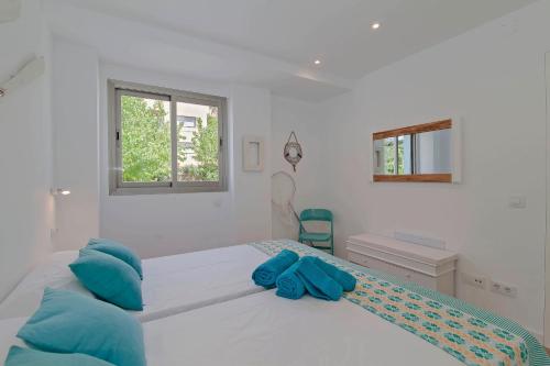 a white bedroom with a large bed with blue pillows at Apartments Beach 4U - Can Pastilla in Can Pastilla