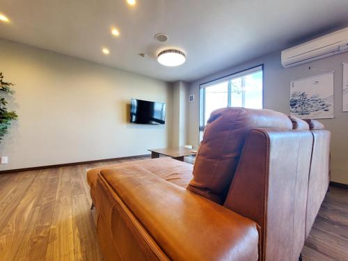 a living room with a leather couch and a television at Shichi no Hotel in Shichigahama