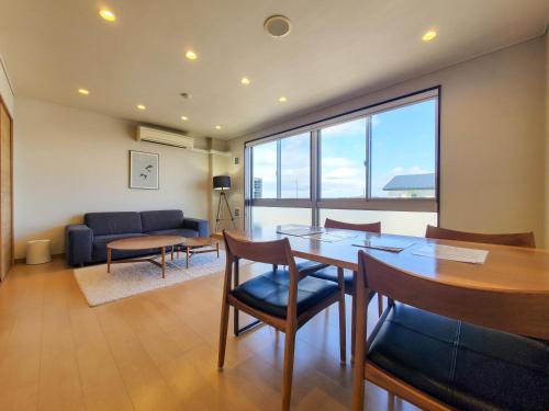 a dining room with a table and chairs and a couch at Shichi no Hotel in Shichigahama