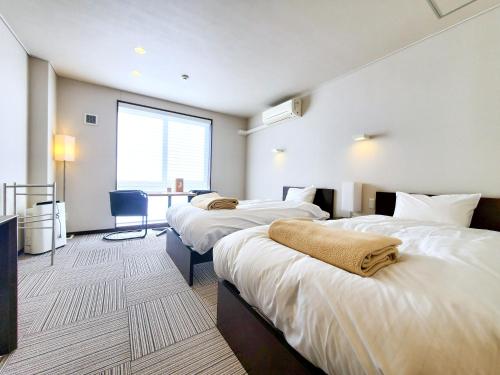 a hotel room with three beds and a table at Shichi no Hotel in Shichigahama