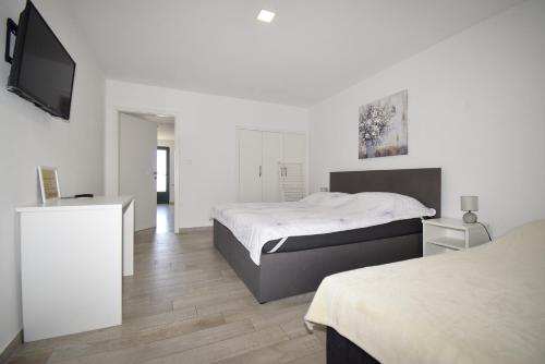 a white bedroom with a bed and a flat screen tv at Stars Palace - apartments and rooms in Jezera
