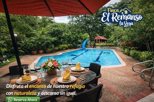 a table with an umbrella next to a swimming pool at Finca El Remanso La Vega in La Vega