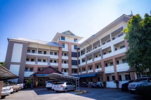a large building with cars parked in a parking lot at Saksiri apartment in Ban Si Than