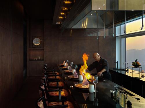 a man preparing food at a long table in a restaurant at Mandarin Oriental, Shenzhen in Shenzhen