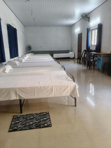 two beds in a large room with tables and chairs at Lagoon celebration10 in Perumanseri