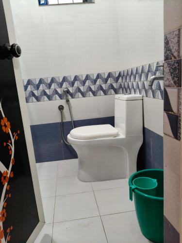 a bathroom with a toilet and a green bucket at Lagoon celebration10 in Perumanseri