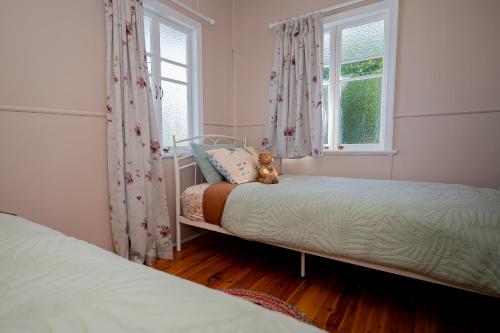 a small bedroom with two beds and two windows at Herbgully Cottage in Roma