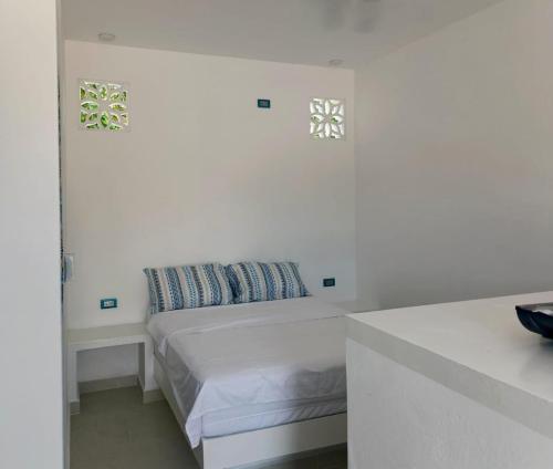 a white bedroom with a bed and two windows at Casa Barcelona in Honda