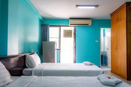 two beds in a room with blue walls at Saksiri apartment in Ban Si Than