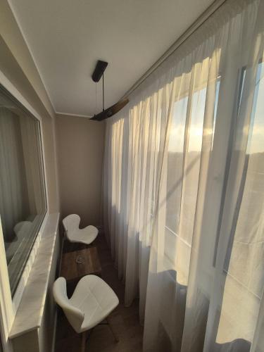 a room with two white chairs and a window at Alpasio Rentals 3 in Galaţi