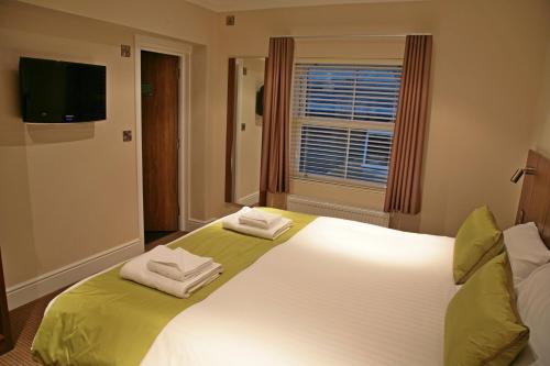 una camera da letto con un grande letto bianco con asciugamani di The Buxted Inn a Buxted