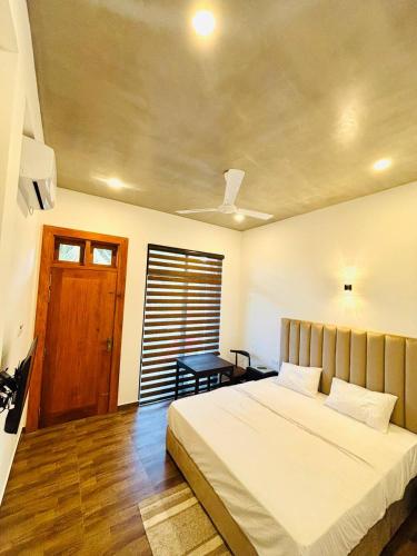 a bedroom with a bed and a table and a door at Ceylan Dream Hiriketiya in Nilwella