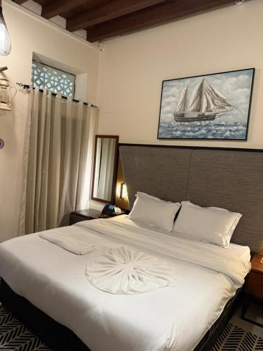 a bedroom with a large white bed with a boat on the wall at Ahmadia Heritage Hiba Guest House - Built in 1916 - Al Ras Metro Station in Dubai