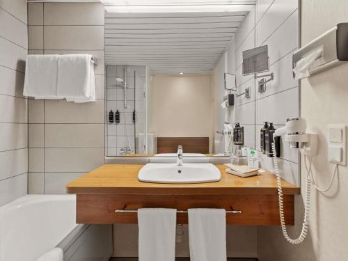a bathroom with a sink and a tub and a shower at Mercure Hotel Hamburg am Volkspark in Hamburg