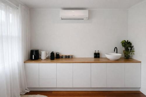 a kitchen with white cabinets and a counter with a sink at Blagdon Close Guesthouse in New Plymouth