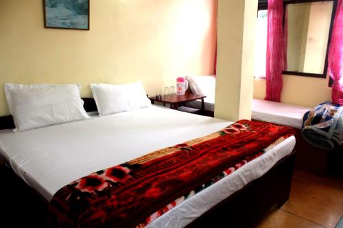 a bedroom with a bed with a red blanket on it at Hotel Lhakhar in Gangtok