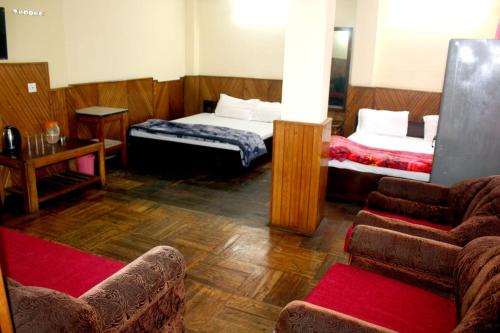 a room with two beds and a couch and chairs at Hotel Lhakhar in Gangtok