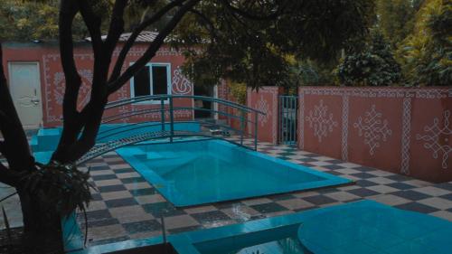 a swimming pool in front of a house with a tree at bethi farms in Malkāpur