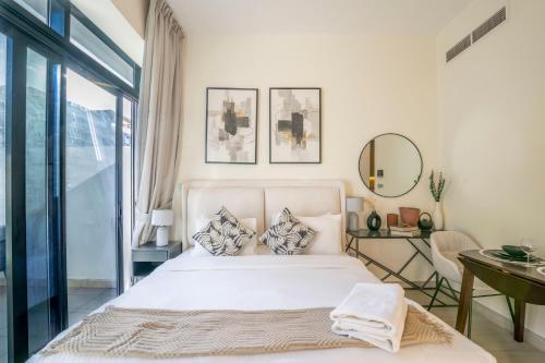 a bedroom with a bed and a table and a mirror at EasyGo - Unbeatable Deals on Urban Rentals in Riviera 16 in Dubai