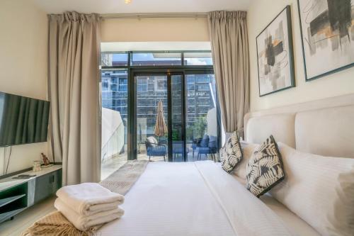 a bedroom with a large white bed and a balcony at EasyGo - Unbeatable Deals on Urban Rentals in Riviera 16 in Dubai