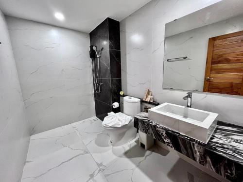 a white bathroom with a sink and a toilet at Ozone hotel khanom in Khanom
