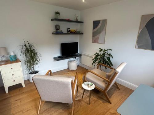 a living room with two chairs and a tv at Cosy cabin nestled in the Surrey Hills in Dorking