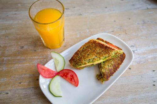 een sandwich en fruit op een bord met een glas sinaasappelsap bij Niños Hotel Fierro in Cuzco