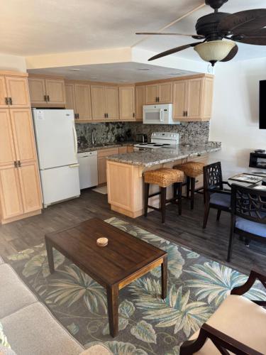 a kitchen with wooden cabinets and a table at The Happy Hideaway - Maui Calm by the Ocean in Kihei