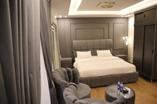 a bedroom with a bed and a chair and a table at Bahria Premium Hotel in Rawalpindi