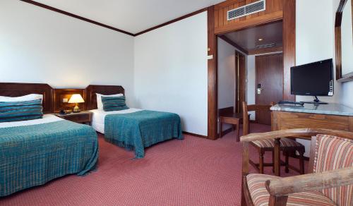 a hotel room with two beds and a flat screen tv at Hotel Lux Mundi in Fátima