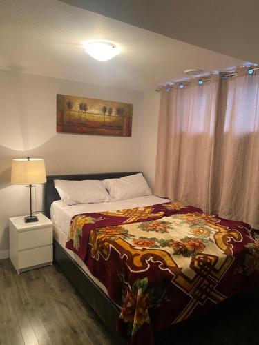 a bedroom with a bed and a lamp and curtains at A cozy 1 bedroom suit in Saskatoon