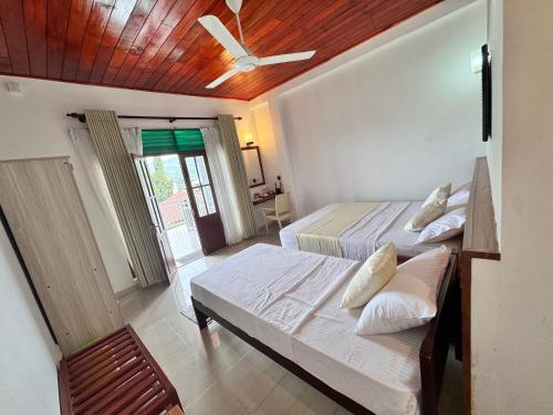 a bedroom with two beds and a ceiling fan at Misty Hills Lakeview Lounge in Kandy