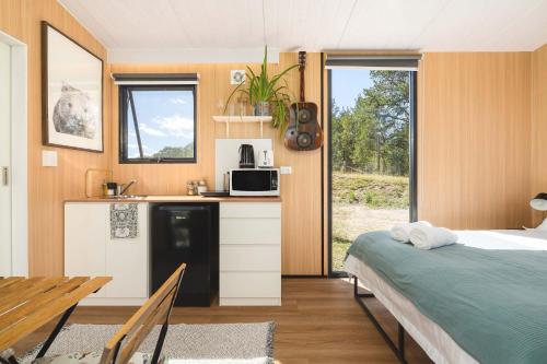 a bedroom with a bed and a kitchen with a microwave at Kanimbla Sunsets by Tiny Away in Kanimbla