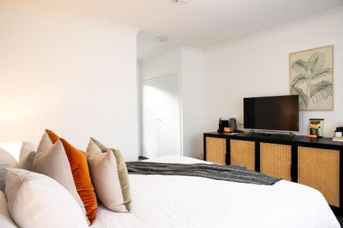 a bedroom with a bed with pillows and a tv at The Oaks Ranch in Tomakin