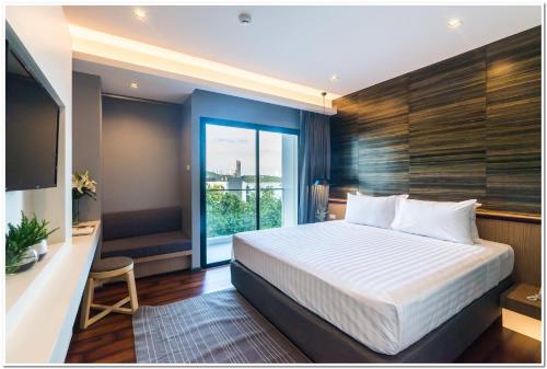 a bedroom with a large bed and a large window at Sea Me Spring Tree Hotel in Pattaya