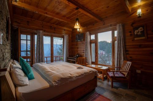 a bedroom with a bed in a log cabin at Ishan Log Huts-A boutique home stay in Banjār