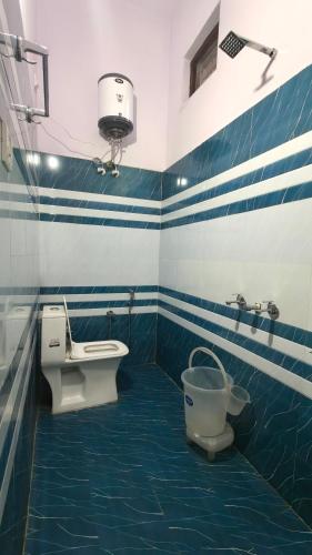 a blue and white bathroom with a toilet and a sink at Amigo's Hotel and Restaurant in Nandaprayāg