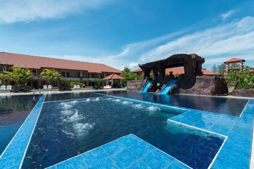 a pool at a resort with a slide at Tok Aman Bali Beach Resort @ Beachfront in Kampong Ayer Tawar